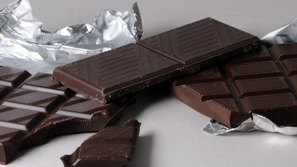 Morceaux de chocolat noir présentés sur leurs feuilles d’aluminium