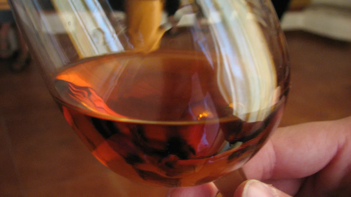 Main faisant tourner un verre de vin pour en observer la robe et les arômes