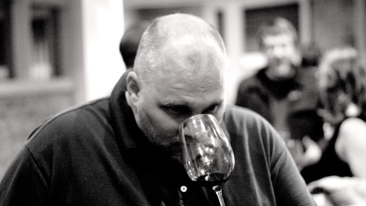 Un homme hume attentivement un verre de vin rouge pendant une dégustation