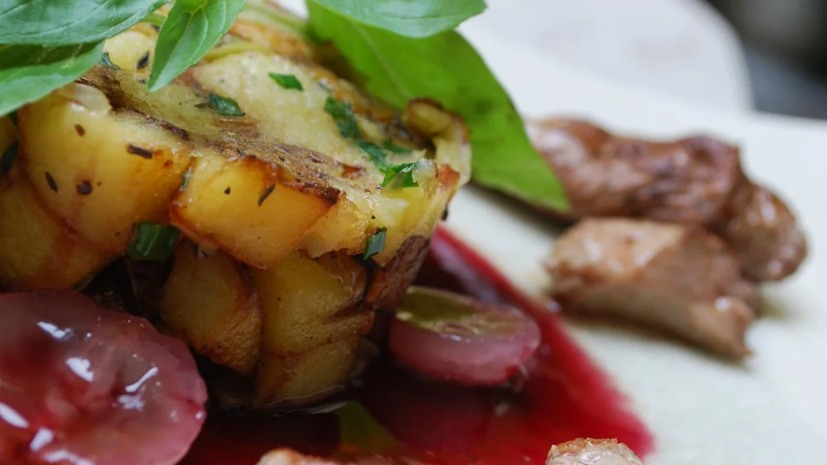 Canard tranché servi avec pommes de terre, raisins et sauce au vin rouge