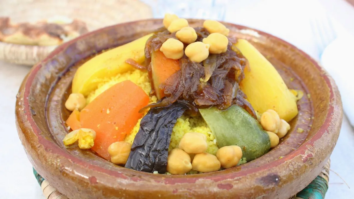 Couscous marocain aux légumes et pois chiches servi dans un plat en terre cuite