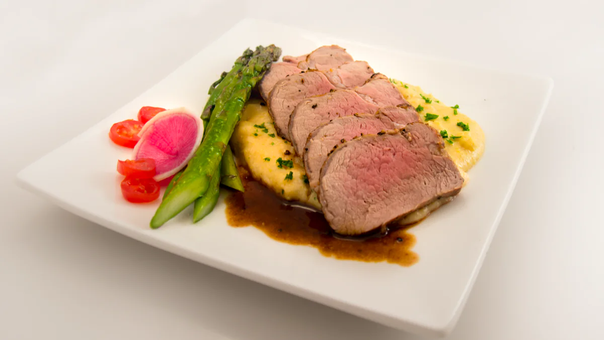 Filet mignon de porc tranché servi avec purée, asperges et légumes