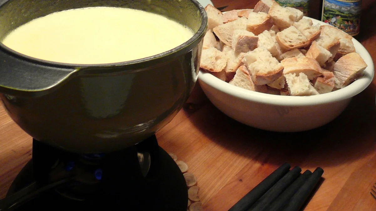 Caquelon de fondue au fromage servi avec des cubes de pain